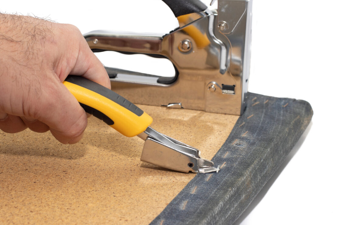 A man uses a specialty tool to remove a staple from fabric